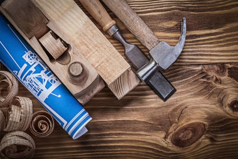Blue construction plan shaving plane claw hammer chisel wooden studs shavings on wood board