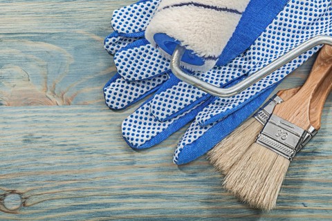Set of paint roller brushes protective gloves on wood board construction concept