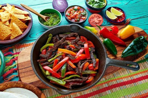 Beef fajitas in a pan with sauces chili and sides Mexican food