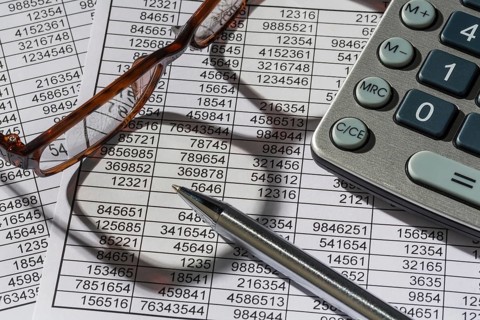 A calculator lies on the figures of a balance sheet and statistics. Symbol photo for turnover,