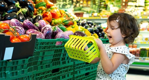 Child shopping eggplants in supermarket. Concept for buying fruits and vegetables in hypermarket.