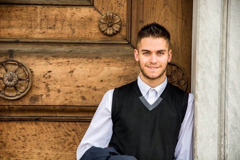 Elegant young man leaning against old wall and wooden door