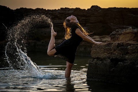 Middle-aged woman dancing and throwing water in the air, Maioris beach, llucmajor, Majorca,