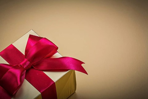 Wrapped present with tied bow on golden background holidays concept