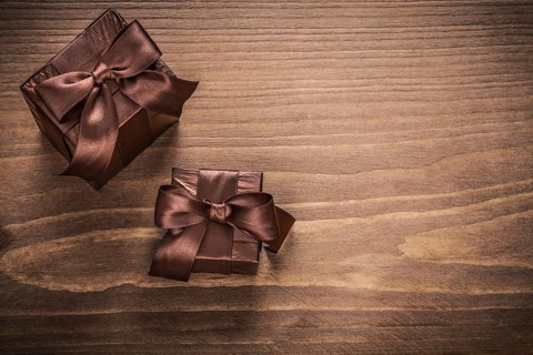 Packed glittery gift containers with bows on vintage wooden board