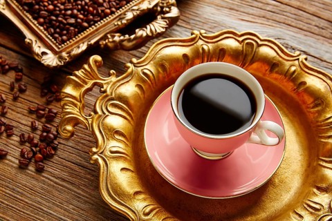 Coffee cup and beans on vintage golden tray in wooden old table