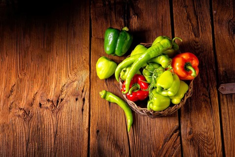Various harvested peppers and hot peppers in a basket