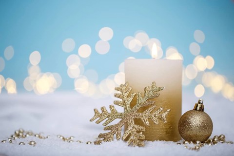 Christmas or new year candle with festive ornaments and bokeh lights on snow, family holidays