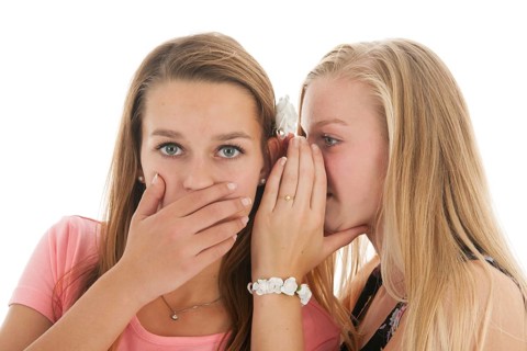 Teen girls are whispering gossip to each other