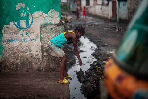 Child throwing rubbish into a gutter on the street, environmental pollution, poverty Kinshasa,