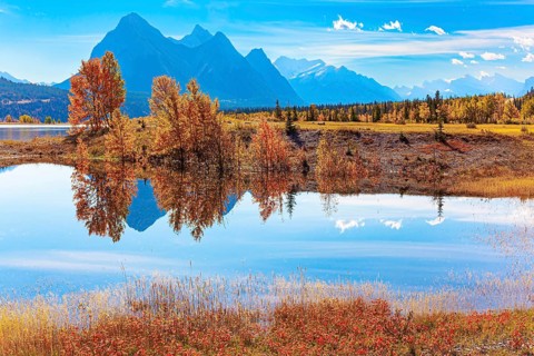 Smooth water of artificial lake Abraham reflects the Rocky Mountains. Sunny day in October.