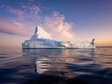 Large glaciers in the bay by the rocky shore in the light of the setting sun
