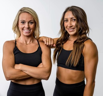 Two gorgeous athletic fit models pose confidently, their toned muscles highlighted by soft lighting