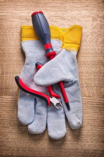 Little nippers screwdriver and protective working glove on wooden board construction concept