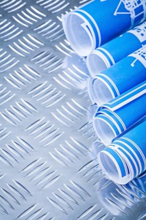 Blue rolled up construction drawings on fluted metal background vertical view