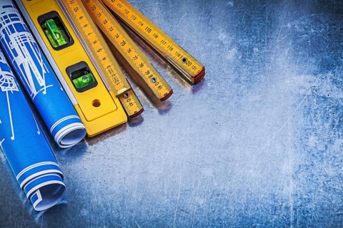 Blue rolled blueprints wooden meter construction level on metallic background