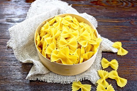 Farfalle pasta in bark box on burlap on the background of dark boards