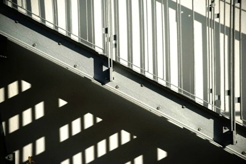 The façade of a residential building with an external staircase that casts a shadow