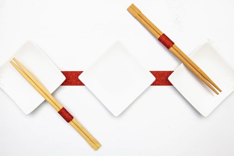 Ceramic bowls and bamboo chopsticks for sushi food with red and white decoration