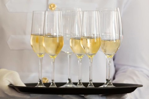 Waiter holds a tray of white wine, champagne and water