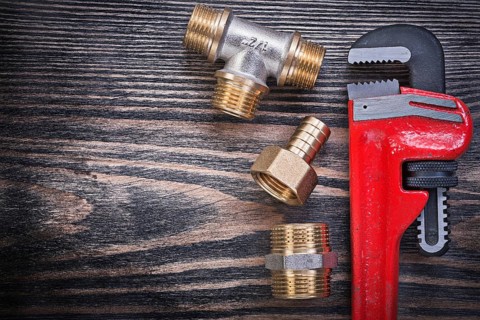 Set of monkey wrench brass equal tee nipple hose connector on wooden board plumbing concept