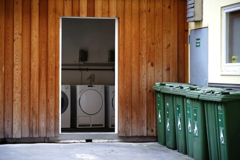 Washing machines next to each other in a storage room in the backyard of an apartment block