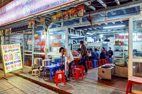 A street restaurant at night with diners at tables and vibrant neon lights, restaurant in the