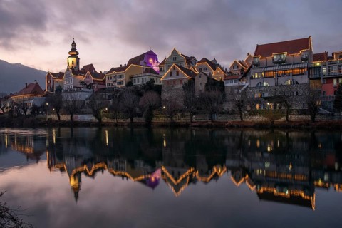 Christmas illuminated house facade of Frohnleiten reflected in the river Mur, Frohnleiten, Styria,