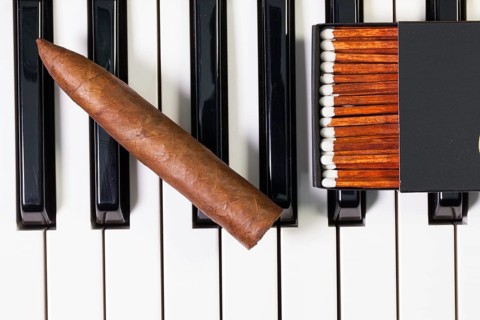 Detail of piano keyboard and luxury cigar
