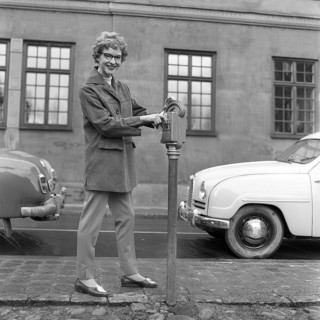 In the 1950s. A woman is pictured in the street and at a parking meter. A device used to pay for