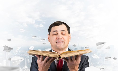 Happy businessman holding open old book. Smiling man in suit standing on downtown background with