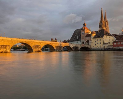 Serene riverside scene at sunset with a bridge, cathedral, and historic town reflecting on the