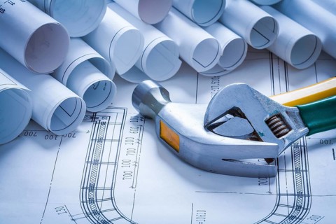 Claw hammer adjustable spanner and pile of blueprint rolls construction concept