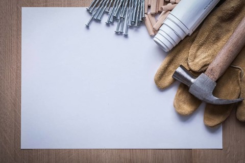 Blueprints sheet of paper steel nails claw hammer wooden dowels and leather protective gloves on