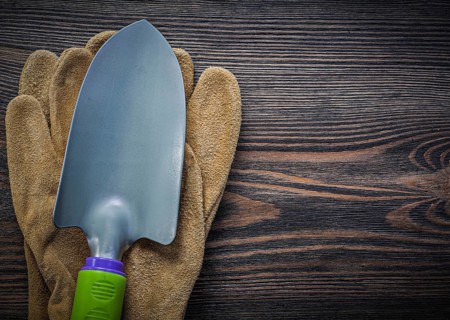 Metal trowel protective gloves on wooden board gardening concept