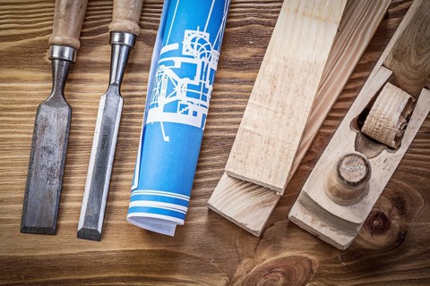 Blue rolled construction drawing shaving plane chisels wooden studs on wood board