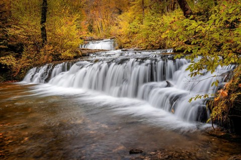 A beautiful autumn forest landscape with idyllic waterfall and pool