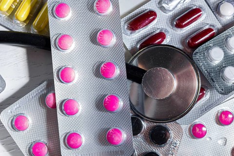 Colorful pills in blisters are lying on the table next to the phonedoscope close-up