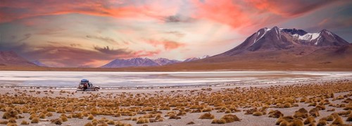 Amazing sky at sunset over Altiplano, Bolivia as an off-road vehicle is driving by