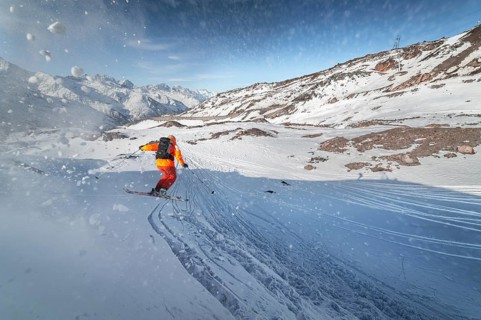 Skier rides on a snowy slope on a sunny day at sunset against the backdrop of the mountains. The