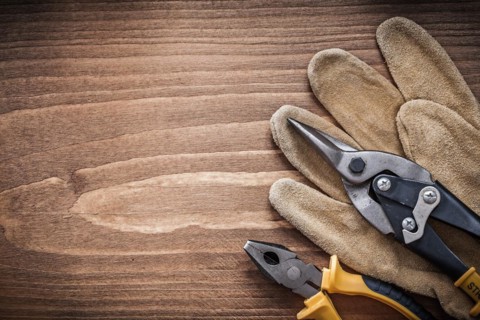 Steel cutter pliers leather safety gloves on wooden board