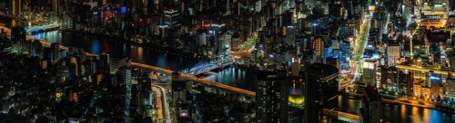 A paorama picture of the Sumida River and nearby cityscape, as seen from above, at night