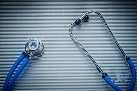 Medical auscultator on striped background