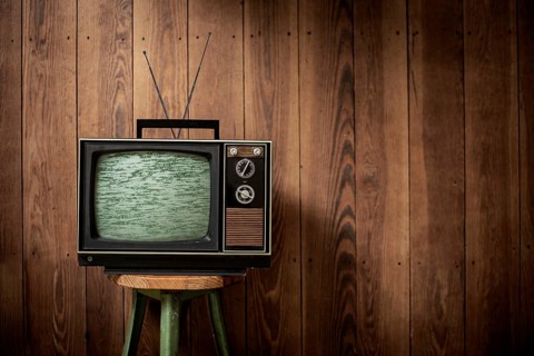 Old television in front of wooden wall
