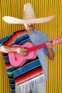 Mexican man with poncho and sombrero playing guitar typical of Mexico