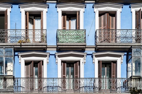 Old colorful residential building in central Madrid with iron balconies and blue stucco facade
