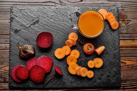 Top view at vegetable background of beets carrots and juice on kitchen table close up view