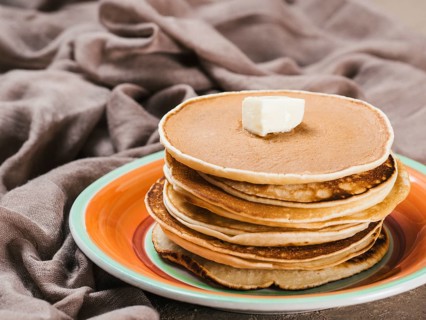 Close up view of homemade pancakes. Stack of pancakes with butter on brown concrete background