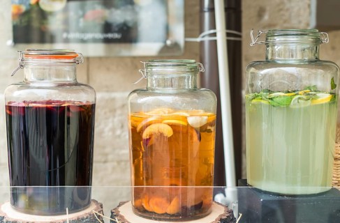 Glass jars filled with lemon, orange and apple juice on wooden stumps
