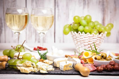 Cheese and salami on a slate board and grape wine